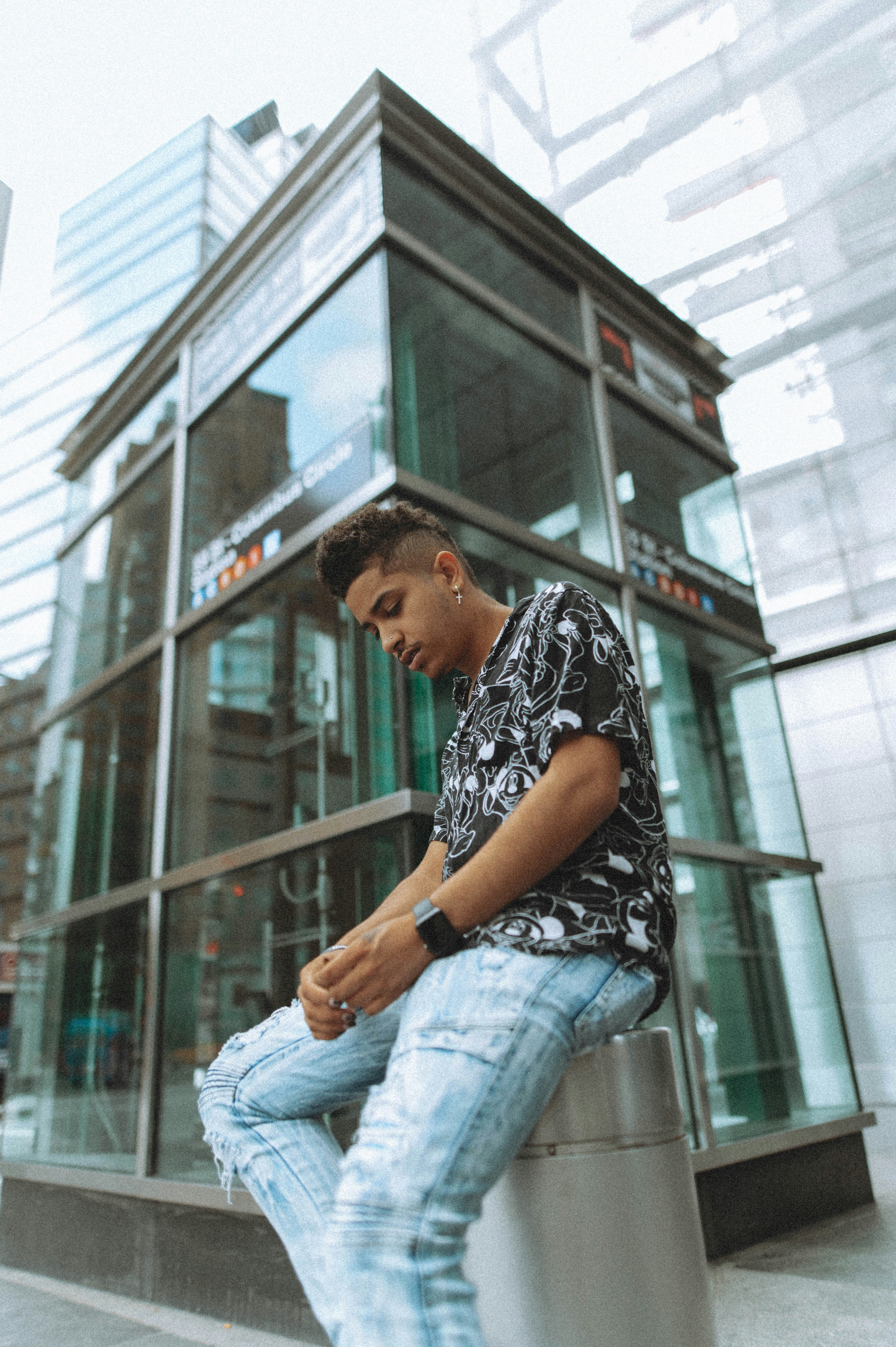 man in black and white shirt and blue denim jeans sitting on window